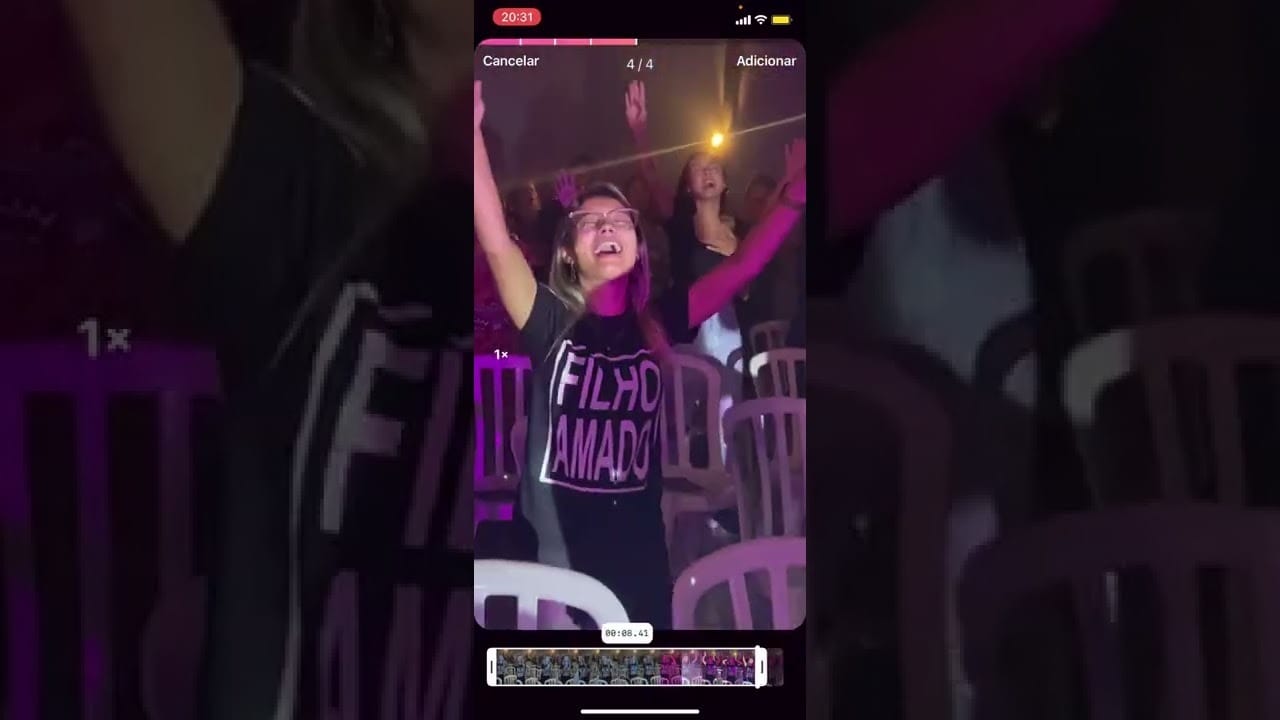 Captura de tela da interface de edição de vídeo de um smartphone, mostrando um clipe de uma jovem (usando óculos e uma camiseta com a frase "FILHO AMADO") com os braços erguidos em adoração durante um evento ou culto. O vídeo sendo editado faz parte da criação de Conteúdo Cristão para distribuição online.